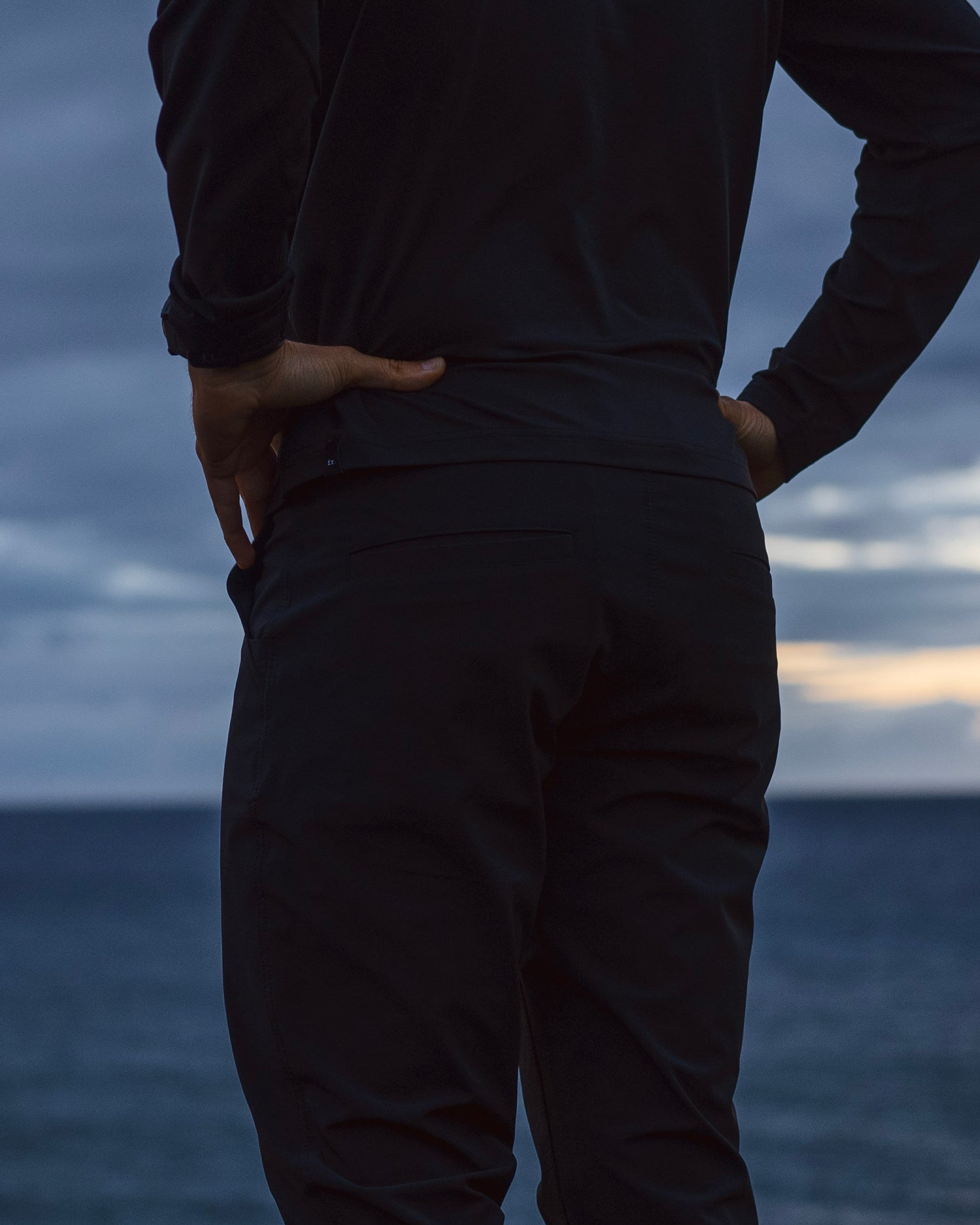 Back shot of the Foreign Rider Co Performance Pants with the Pacific ocean and sunset in the background