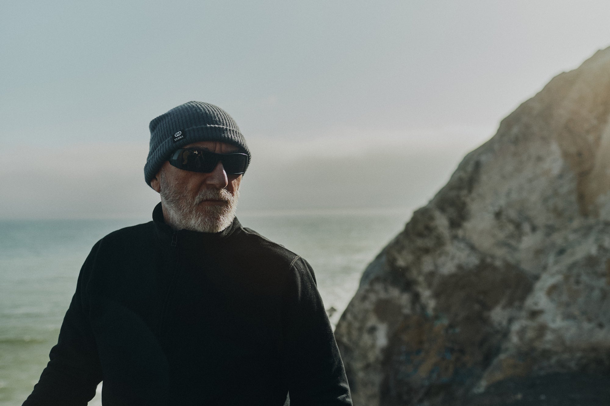 Ralph Dunning standing on a cliff that overlooks the Pacific ocean wearing the Foreign Rider Quarter Zip Sweatshirt