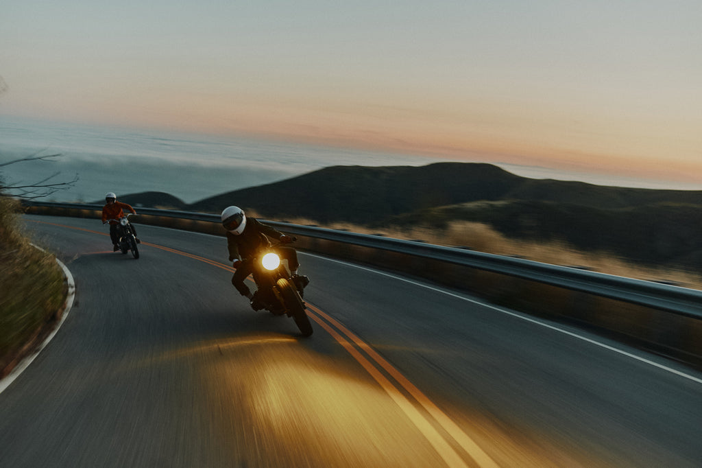 2 men riding motorbikes on the Pacific Coast Highway wearing the Foreign Rider Co Waxed Canvas Utility Jacket