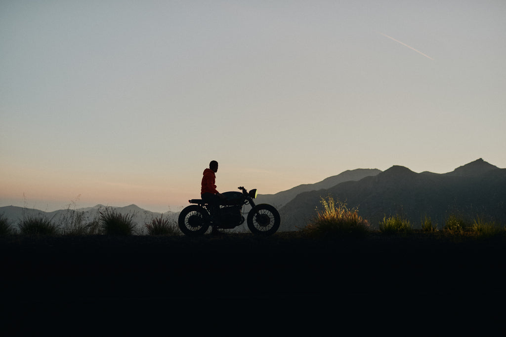 Man sitting on idle motorcycle overlooking Malibu landscape and sunset