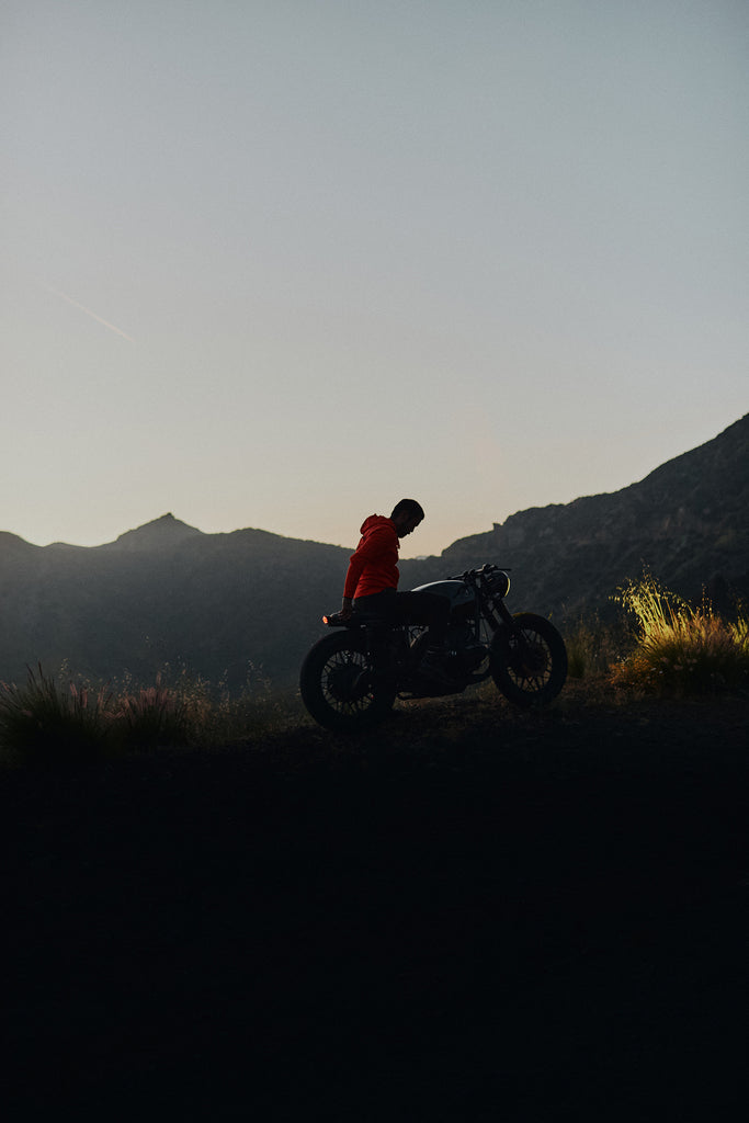Man sitting on a vintage motorbike at sunset wearing the Foreign Rider Full Zip Hooded Vintage Sweatshirt