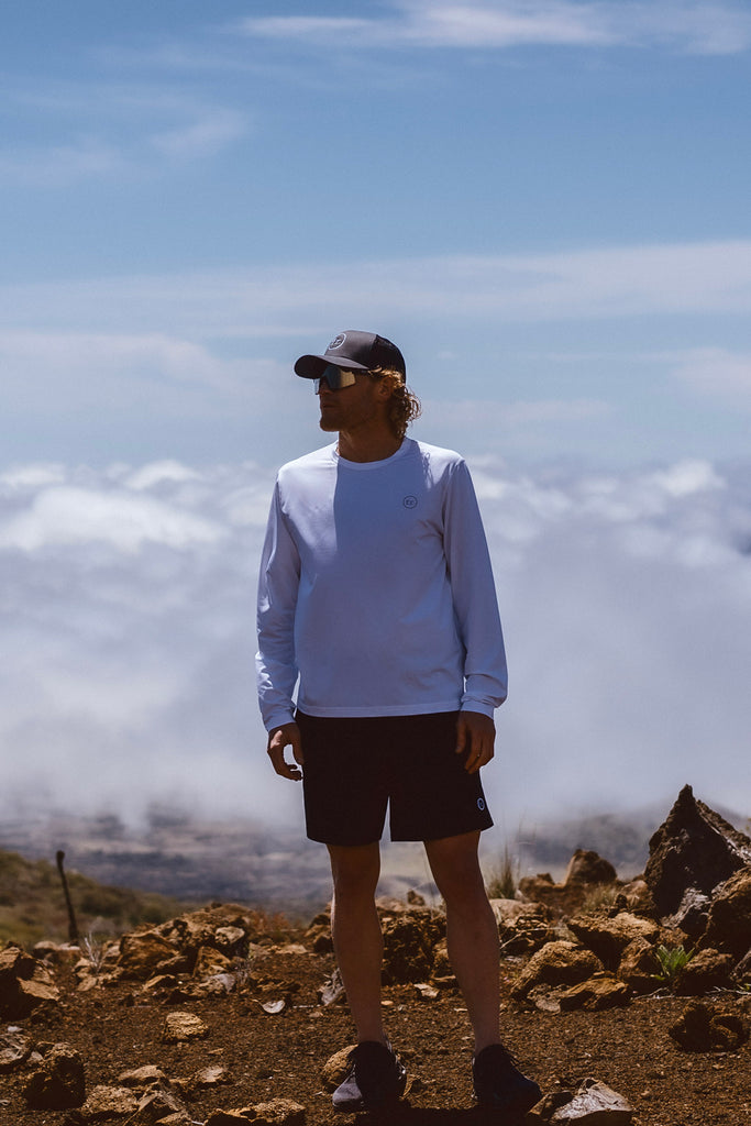Eric Lagerstrom standing above the clouds on a barren rocky mountain wearing the Foreign Rider FR. Performance Long Sleeve T-Shirt