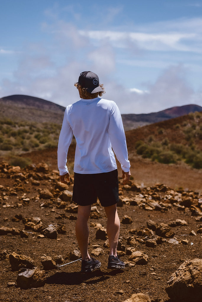 Back shot of Eric Lagerstrom standing on rocky barren landscape wearing the Foreign Rider FR. Performance Long-Sleeve T-shirt