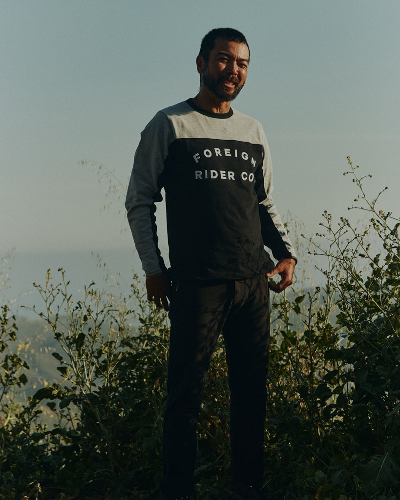 Man standing in front of bushes wearing Foreign Rider Long Sleeve Moto Jersey T-shirt