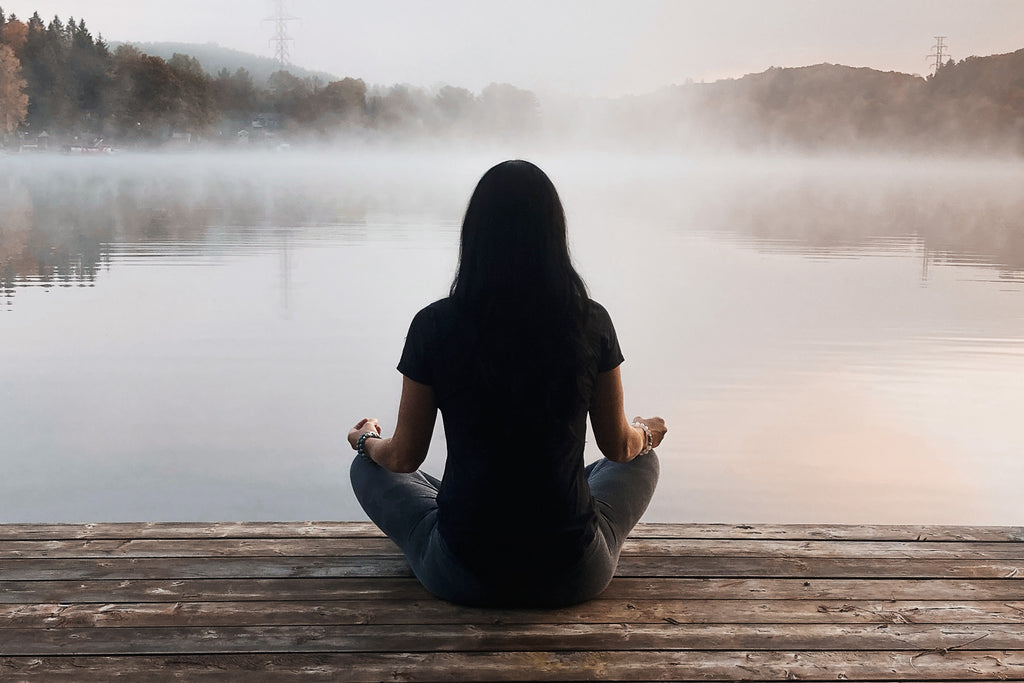 Shannon Kemp meditating on a dock over an early morning foggy lake