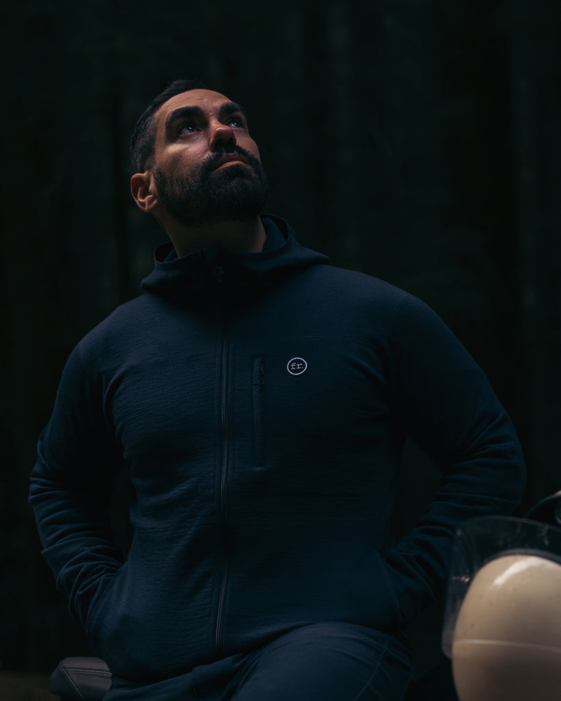 Man leaning on motorbike look up wearing Foreign Rider Co Merino Hooded Jacket