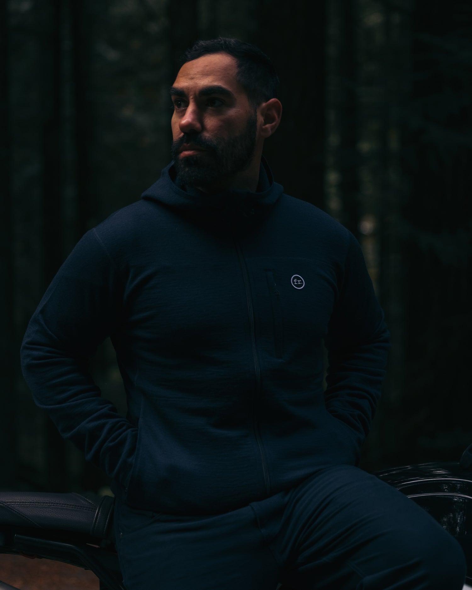 Man sitting on side of motorbike wearing Foreign Rider Co Merino Hooded Jacket