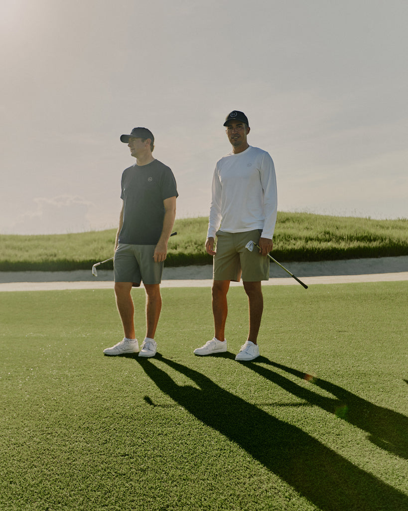 Two men on Grove XXIII golf course holding irons wearing Foreign Rider Performance Shorts