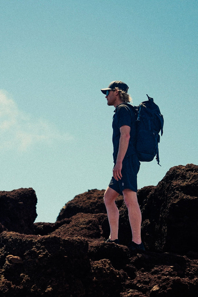 Eric Lagerstrom standing on lava rocks looking off in the distance wearing Foreign Rider FR. Utility Boardshorts