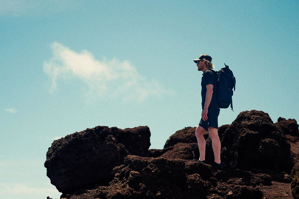 Eric Lagerstrom standing on lava rocks looking off in the distance wearing Foreign Rider FR. Utility Boardshorts