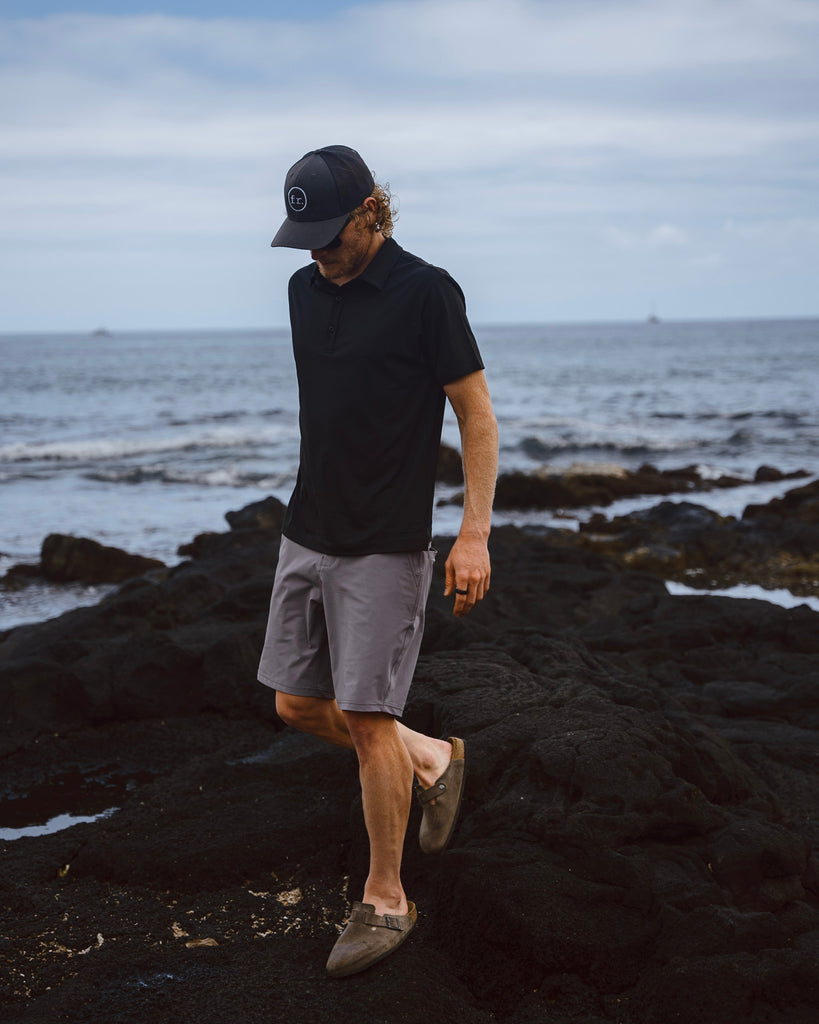 Eric Lagerstrom walking on lava rock Hawaii Island shoreline wearing the Foreign Rider Performance Polo