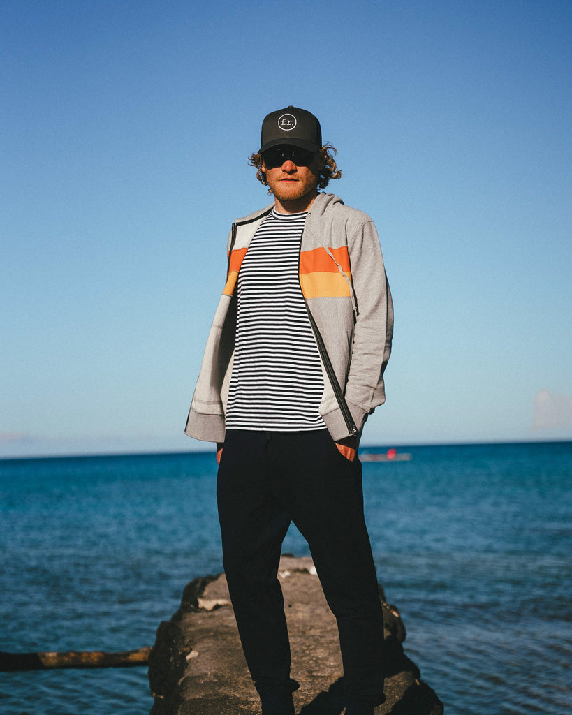 Eric Lagerstrom standing on a rock wearing Foreign Rider clothing with the Pacific Ocean in the background