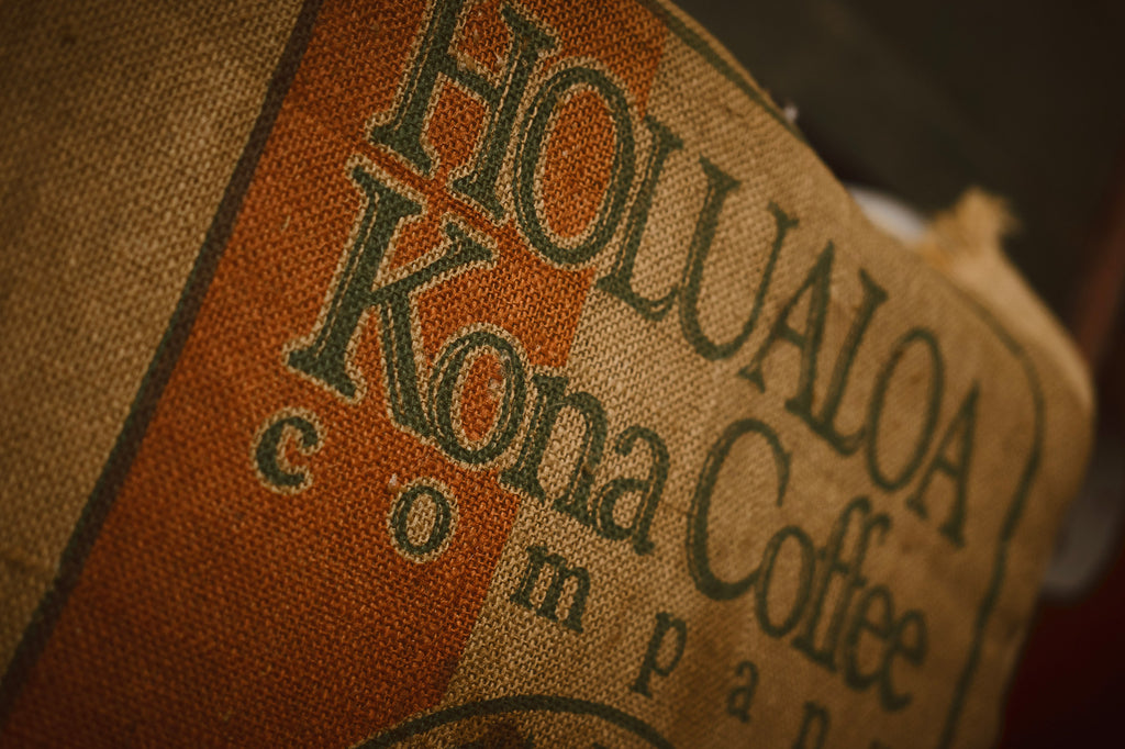 Close up shot of Hōlualoa Kona coffee company logo on a burlap sack holding coffee