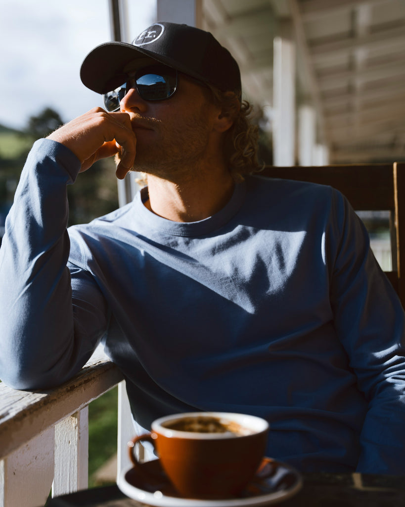 Eric Lagerstrom sitting with a cup of espresso at Waimea coffee company wearing Foreign Rider clothing