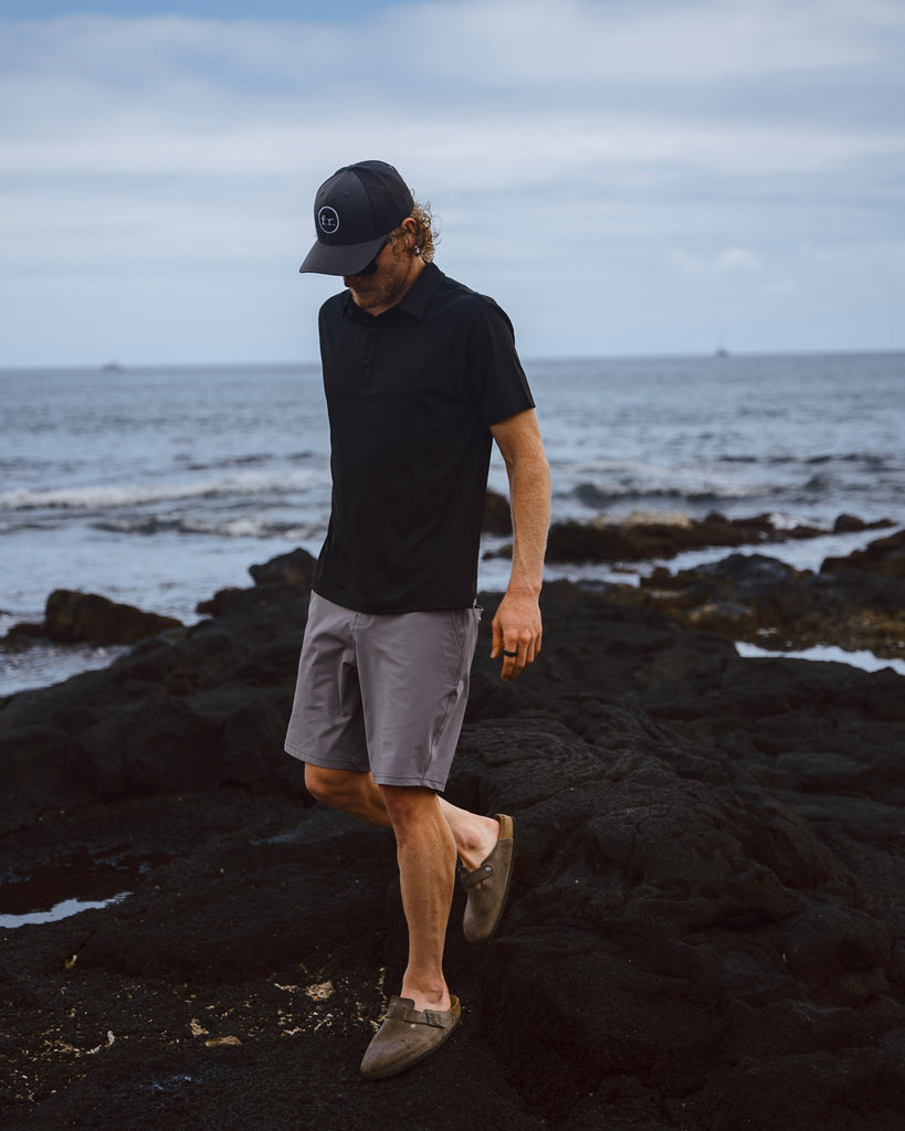 Eric Lagerstrom walking on rocks of shoreline wearing Foreign Rider Co apparel