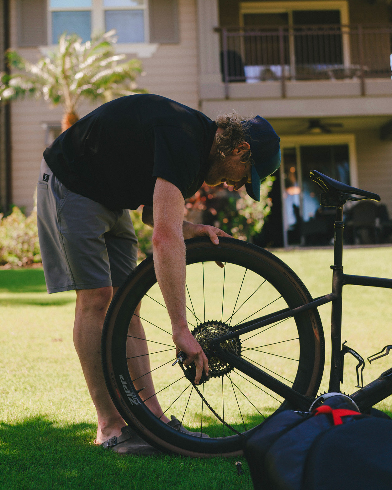 Eric Lagerstrom in a Hawaii Island front yard working on his bicycle wearing Foreign Rider clothing