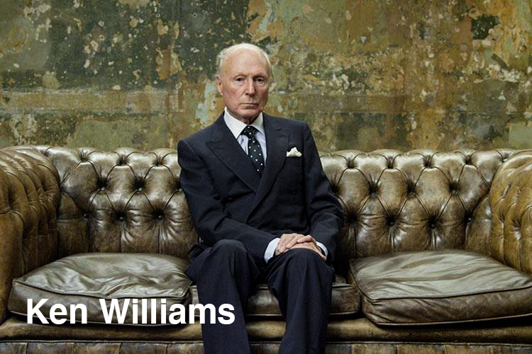 Ken Williams wearing a classic suit sitting on worn out leather couch